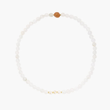 Three layered white beaded bracelets with carved orange agate lotus centerpiece and freshwater pearls on cream background.