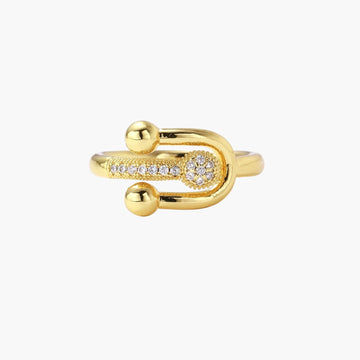 Gold-plated brass ring with safety pin design featuring pavé cubic zirconia stones and dual sphere ends